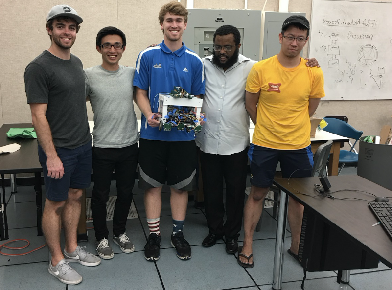 Samuel Semahegn stands with his UCLA team while holding a robot prototype.