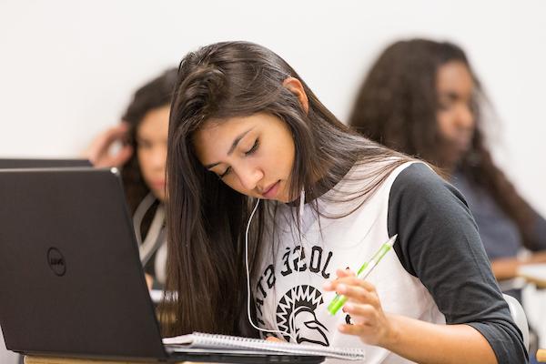 student sitting on desk working on a laptop