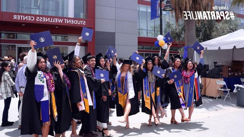 Graduates cheering with their diploma outside of the event center.