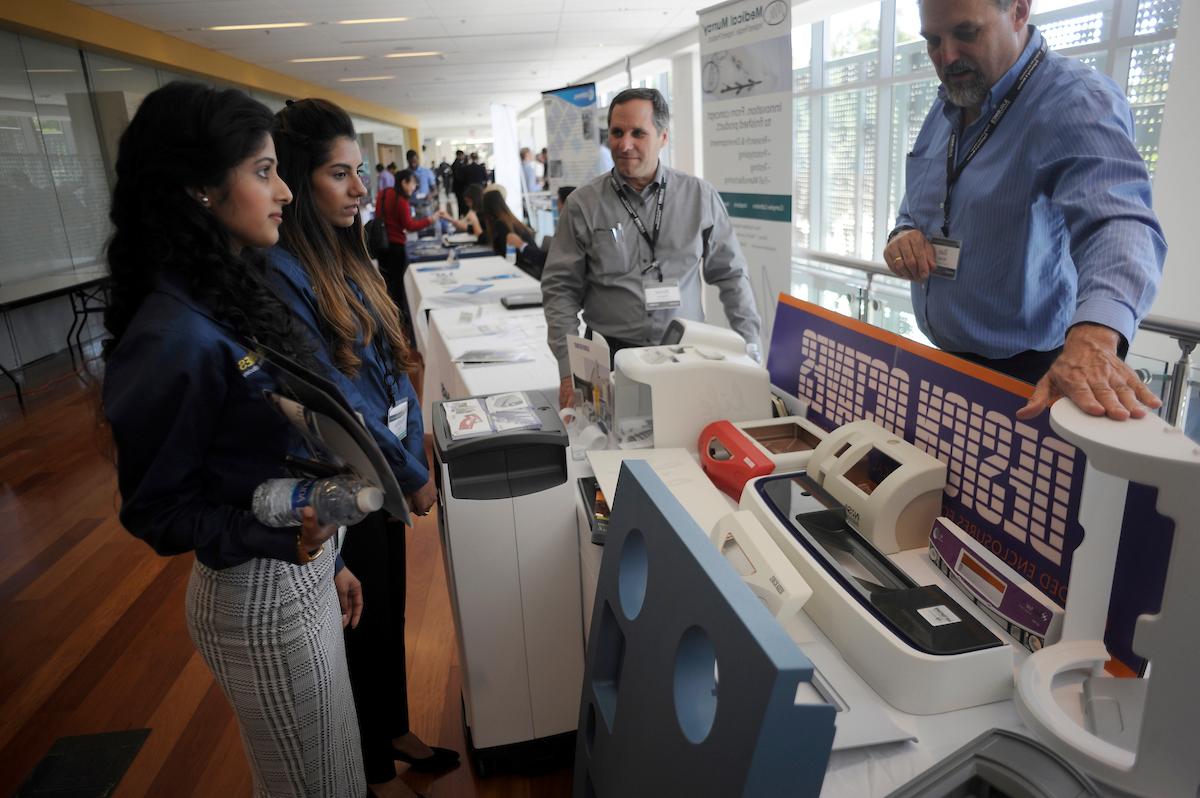 Students visit a table and listen to a vendor at the Biomedical Conference.