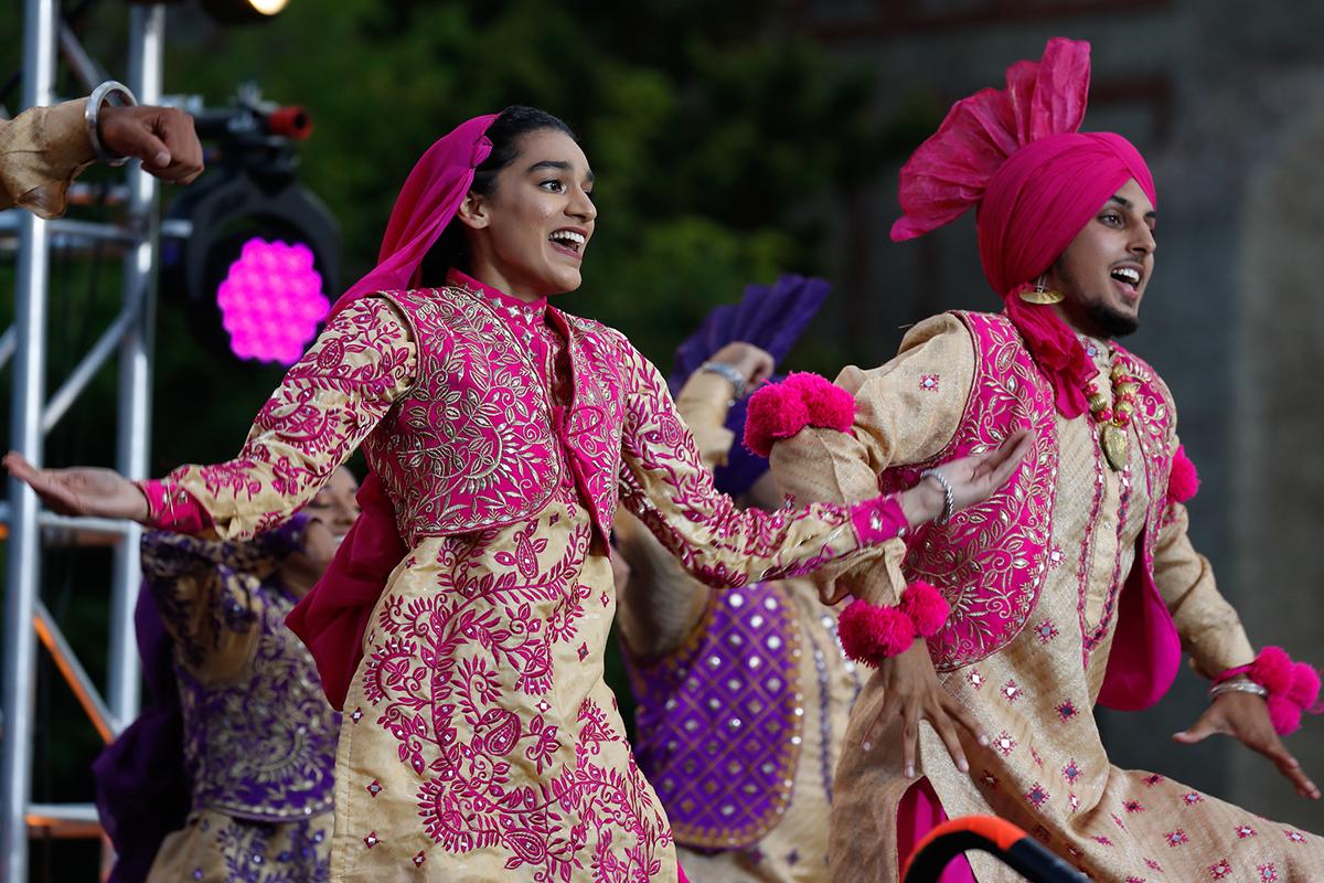 Students dressed in colorful cultural traditional clothing dancing at an event.