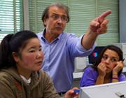 two students and one professor in class, the professor is pointing.