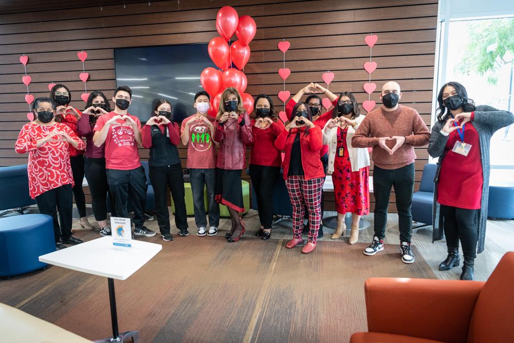 菠菜网lol正规平台 president with students and staff making a heart sign with their hands.